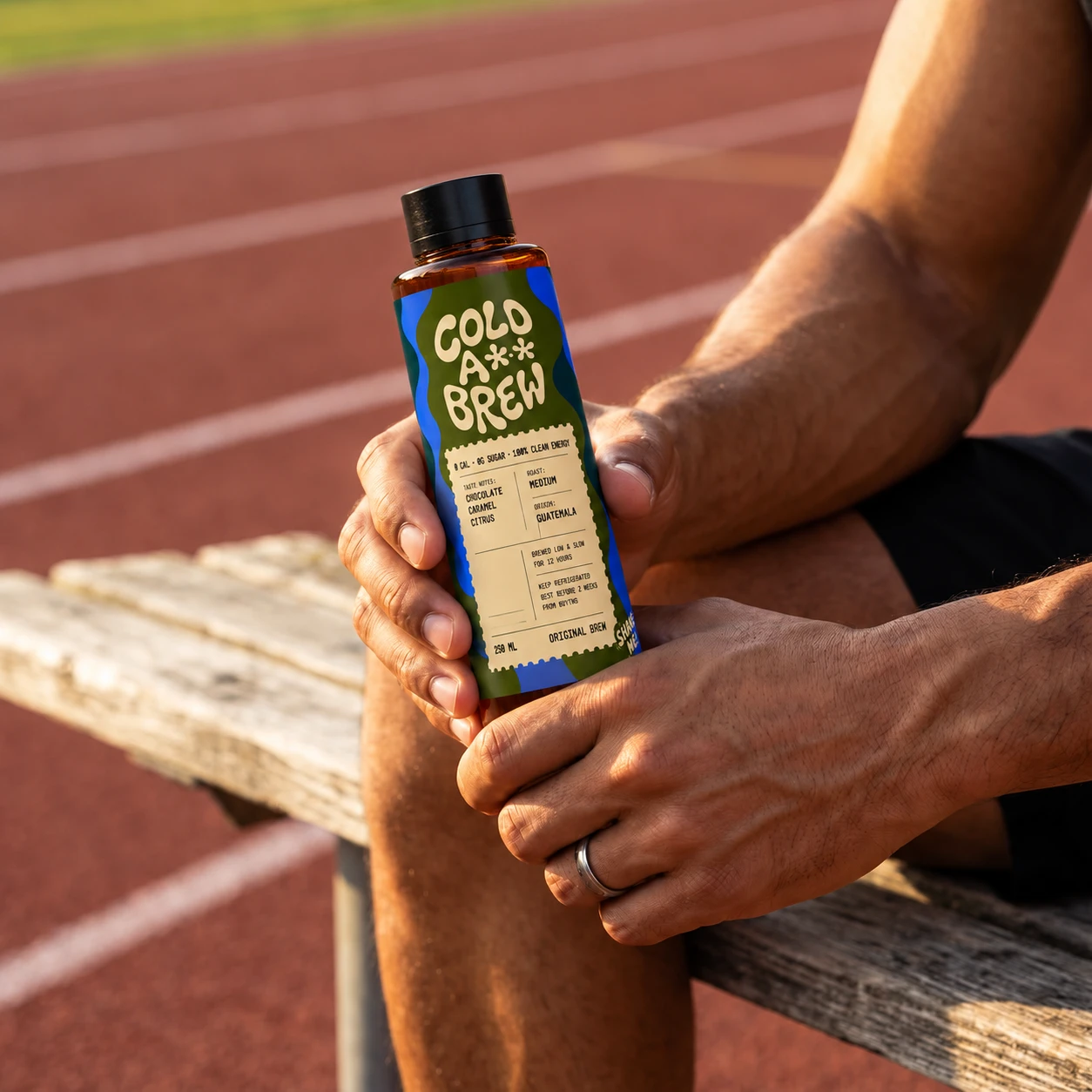 A runner resting on a trackside bench with a bottle of Cold A** Brew